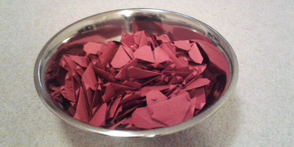 A Stainless Steel Bowl filled with paper hearts.